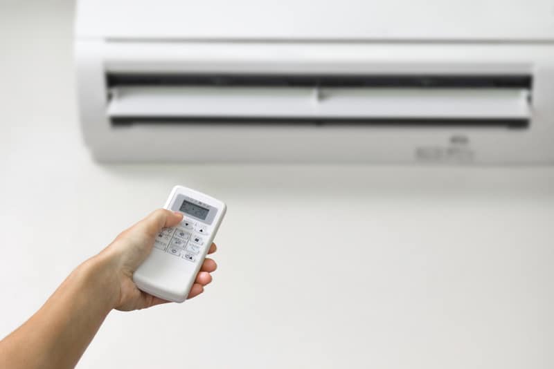 Hand Holding Remote Control of the Air Conditioner — Air Conditioning Professionals in Forster, NSW