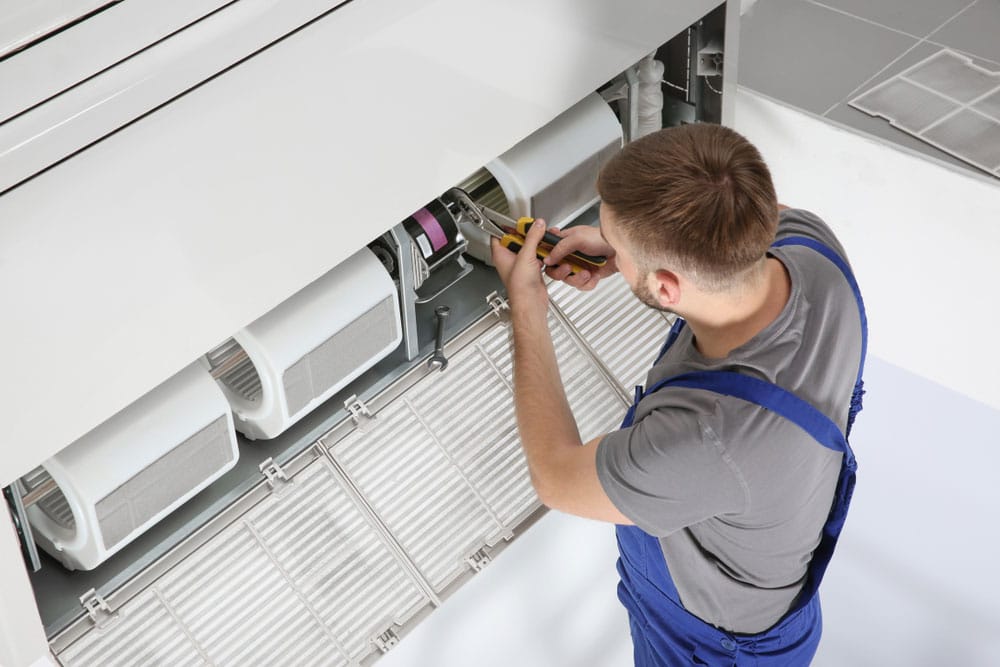 Male Technician Repairing Air Conditioner — Air Conditioning Professionals in Forster, NSW