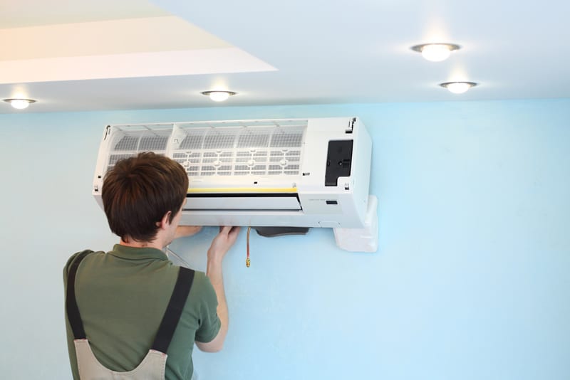 Worker Installs Air Conditioner in the Room with Blue Walls — Air Conditioning Professionals in Taree, NSW